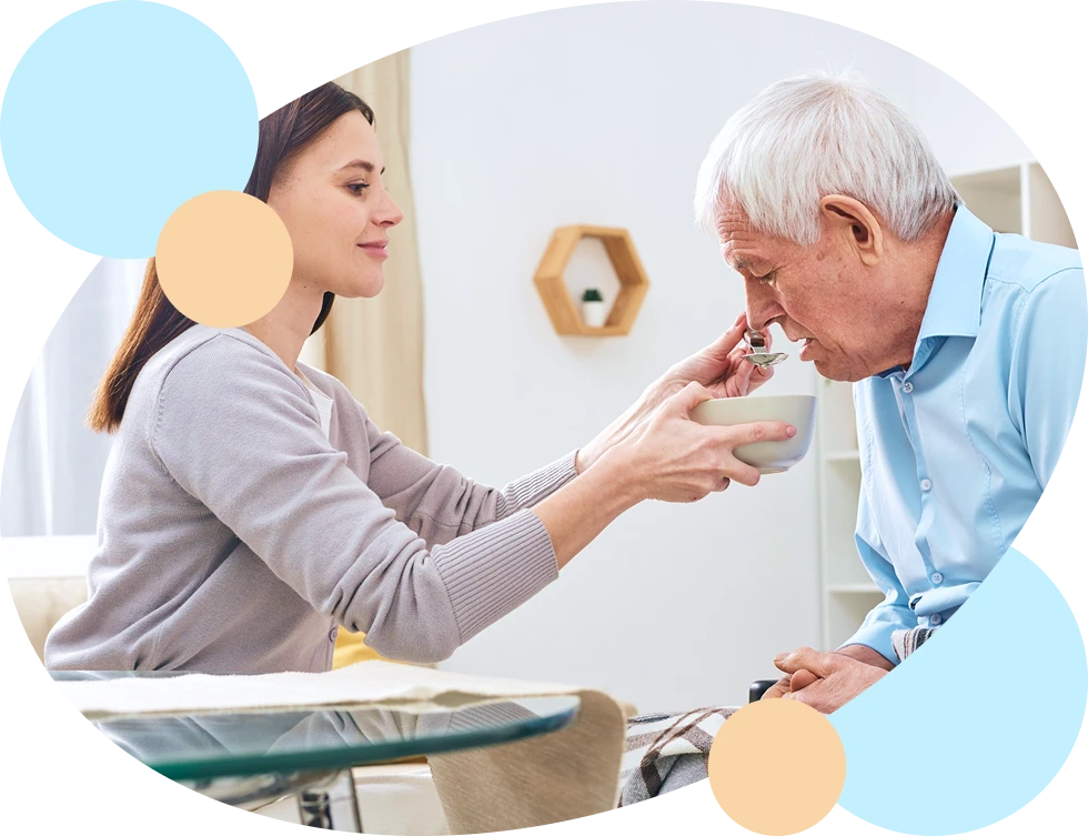 Pflegekraft hilft Senior beim Trinken