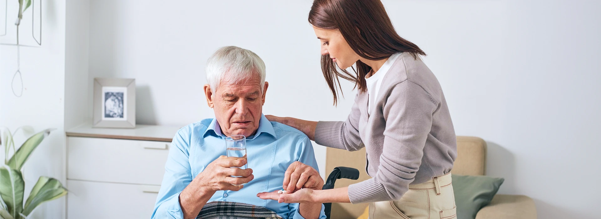 Betreuerin reicht Senior Tabletten