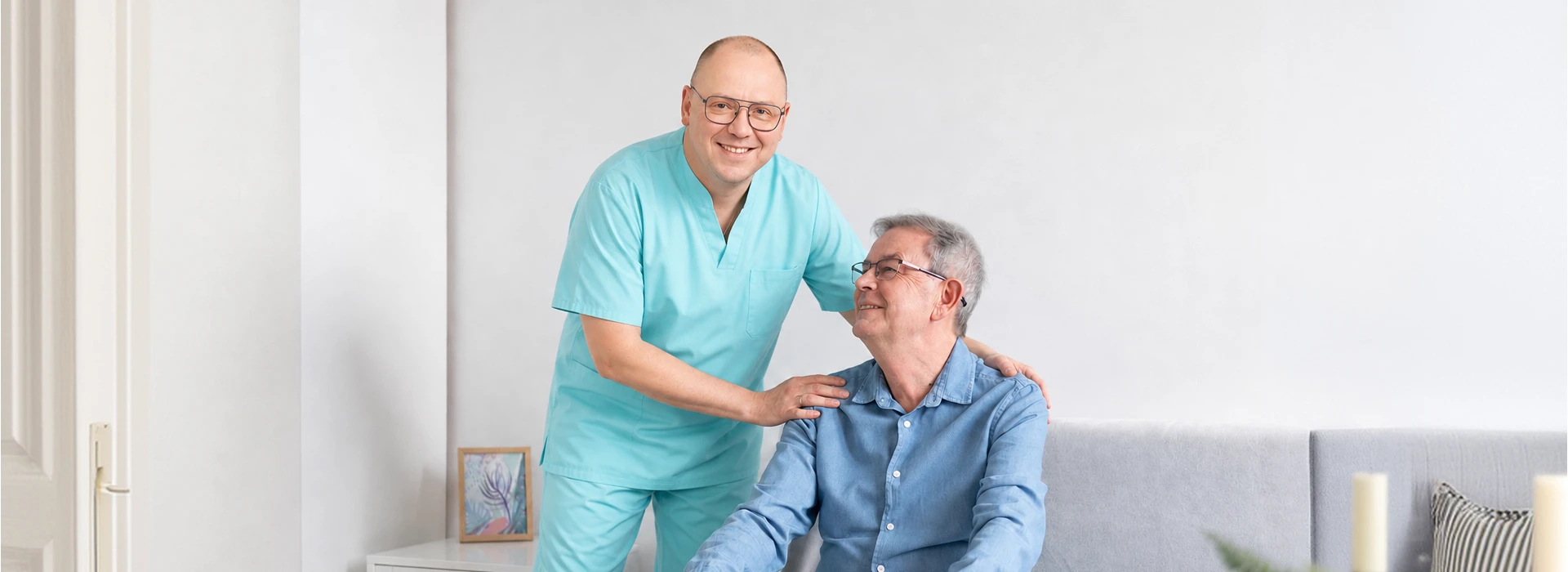 Pflegekraft unterstützt Senior im Sitzen